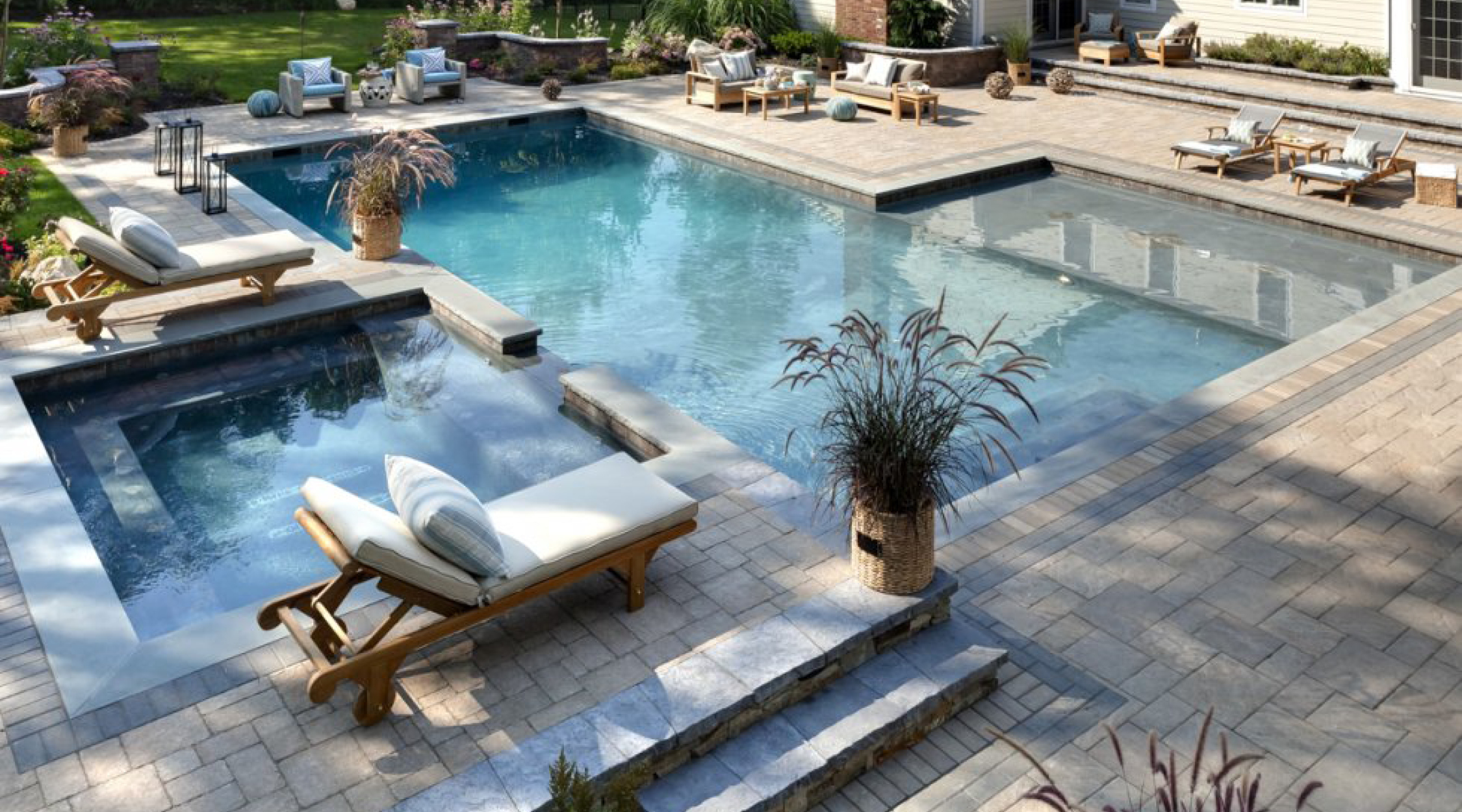 Finished outdoor living space with a pool, stone terrace, and planting